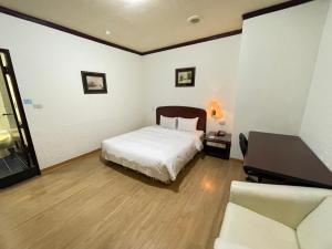 台南亚伯大饭店的一间卧室配有一张床、一张桌子和一张沙发