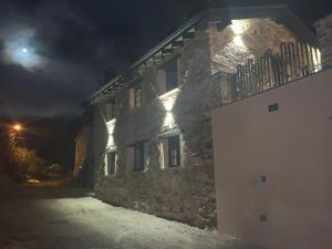 PiluPeta Casa de Aldea的一座石头建筑,晚上在建筑的一侧有灯光