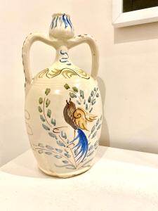 圣凯撒利亚温泉Casa Smeraldo Salento, a strapiombo sul mare的白色的花瓶,上面有鸟和花