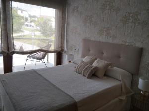 桑亨霍Chalet con vista a las Islas Cíes的卧室配有带枕头的床铺和窗户。
