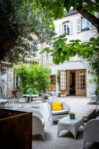 博讷Les Remparts Hôtels et Demeures Historiques的庭院配有桌椅和黄色枕头