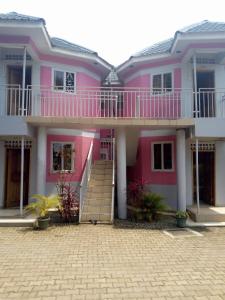 MbaleR&R Gardens Hotel的粉红色的房子,前面有楼梯