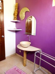佩母德兰巴厘岛欧亚瑟度假酒店的一间带一个碗水槽和紫色墙壁的浴室