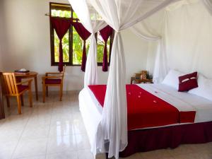 佩母德兰巴厘岛欧亚瑟度假酒店的一间卧室配有一张红色和白色天蓬床
