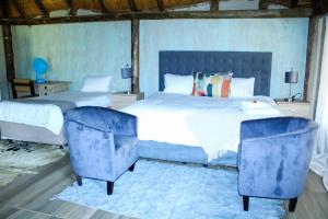路易特里哈特Harnham Mountain Lodge的一间卧室配有一张大床和两张蓝色椅子