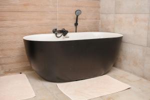 路易特里哈特Harnham Mountain Lodge的浴室设有黑色浴缸,有2个地毯