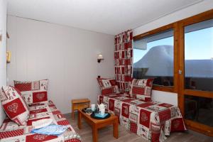 美贝尔Résidence Odalys Le Hameau du Mottaret的客厅配有红色和白色的椅子和窗户