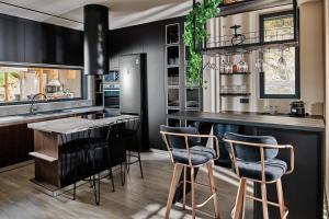 扎金索斯镇Althea Lavish Estate - Villa & Suite的厨房配有黑色橱柜和带吧台凳的台面