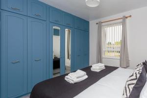 爱丁堡Lovely 2-bed upper villa in Kirkliston Edi Airport的蓝色卧室,配有带毛巾的床