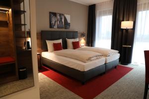雷根斯堡Hotel INCLUDiO的一间卧室配有一张带红色枕头的大床