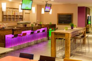 法尔先特Explorer Hotel Garmisch的一间设有紫色和绿色酒吧凳子的餐厅
