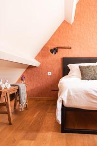 LievegemB&B Maison Lize的一间卧室设有橙色的墙壁、一张床和一张桌子