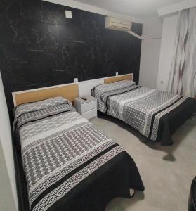 拉利内阿-德拉康塞普西翁拉坎帕纳旅馆的一张黑墙客房内的两张床