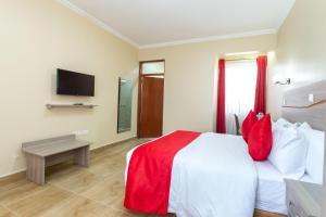 纳库鲁Rock Hyrax Hotel的一间卧室配有一张带红色枕头的床和电视。