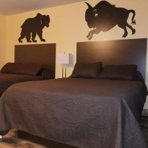兰德Frontier Lodge的卧室配有一张床,墙上挂着两只公牛