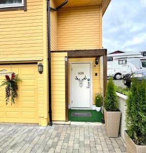 特罗姆瑟Guesthouse in Tromso center by Dada的黄色的房子,有白色的门,上面有鹿