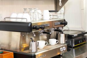 纳库鲁Rock Hyrax Hotel的厨房里的咖啡机,上面有杯子