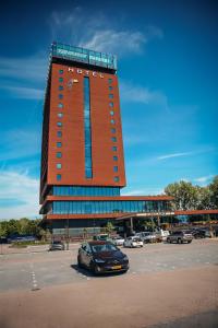 斯希丹Van der Valk Hotel Schiedam的停车场内有停车位的大型建筑