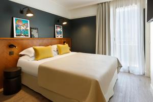 格勒诺布尔RockyPop Grenoble Hotel的卧室配有一张带黄色枕头的大型白色床。