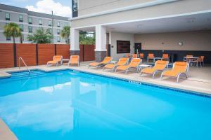 彭萨科拉彭萨科拉大学区假日酒店的一个带橙色椅子和桌子的游泳池