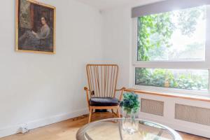 伦敦Spacious 1 Bedroom Apartment in Vibrant Angel的一间设有玻璃桌、椅子和绘画的房间