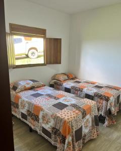巴纳内拉斯Chalés Samambaia的带窗户的客房内设有两张单人床。