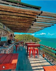 邦比尼亚斯Tainha da Praia Aparthotel的餐厅设有红色的桌子,后面是大海