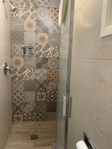 提华纳大理套房酒店的浴室里设有玻璃门淋浴