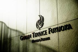 福冈Garden Terrace Fukuoka的瓷砖墙边的标志