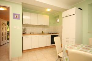 拉斯托伏Holiday house Lastovo - 8289的厨房配有白色橱柜、桌子和用餐室。