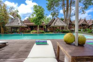 乌鲁瓦图My Dream Bali的一个带游泳池和一张桌子的度假村,上面有椰子