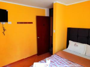 万卡约Hospedaje Las Lilas的一间卧室设有黄色的墙壁、一张床和红色的门