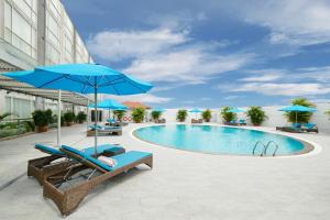 胡志明市思廷西贡格兰德酒店的一座带蓝色遮阳伞和椅子的游泳池位于一座建筑旁边