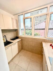 苏利纳Apartment modern in Sulina的小厨房配有白色橱柜和窗户。