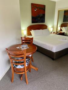 波高尔宾Beautiful Villa in the heart of the Hunter Valley的酒店客房配有一张床、一张桌子和一张床