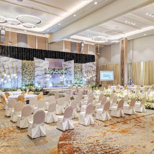 巴淡岛中心巴塔姆中心哈里斯酒店的一个带白色椅子和舞台的宴会厅