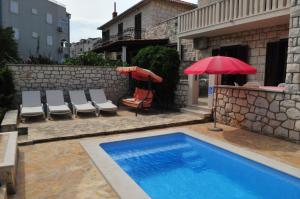 苏佩塔尔Seaside apartments with a swimming pool Supetar, Brac - 11360的一个带红色遮阳伞和椅子的游泳池