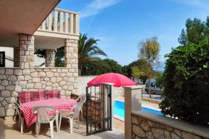 苏佩塔尔Seaside apartments with a swimming pool Supetar, Brac - 11360的游泳池旁的一张桌子和一把红伞
