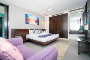 卡伦海滩Karon Sea View Beach Apartment的一间卧室配有一张床和一张紫色沙发