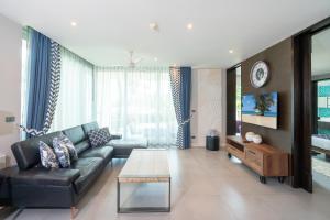 卡伦海滩Karon Sea View Beach Apartment的客厅配有黑色真皮沙发和电视