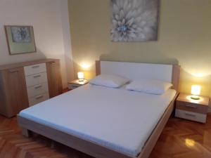 特罗吉尔Apartments by the sea Arbanija, Ciovo - 11321的一间卧室配有一张带两盏灯的大型白色床。