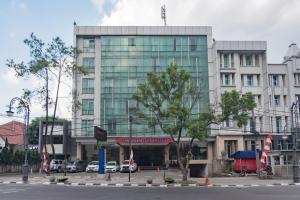 万隆Urbanview Hotel Newton Riau Bandung by RedDoorz的一座大型建筑,前面有汽车停放