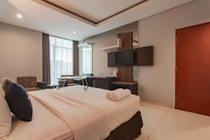 万隆Urbanview Hotel Newton Riau Bandung by RedDoorz的酒店客房设有一张大床和一张书桌。