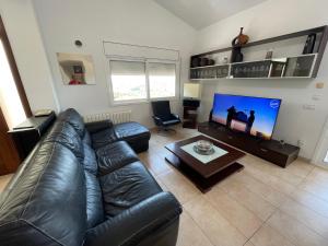 布拉内斯Villa for 2 families的客厅配有真皮沙发和平面电视