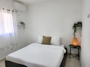 埃拉特Melony Apartments Yam Suf Street的白色卧室配有床和边桌