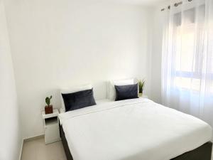 埃拉特Melony Apartments Yam Suf Street的白色的窗户客房内的一张白色的床