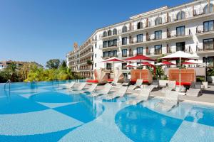 马贝拉Hard Rock Hotel Marbella - Puerto Banús的大楼前的游泳池配有椅子和遮阳伞