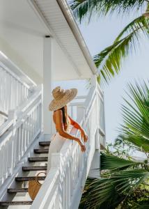 圣吉尔莱班留尼汪岛星礁度假村的站在房子楼梯上的稻草帽上的女人