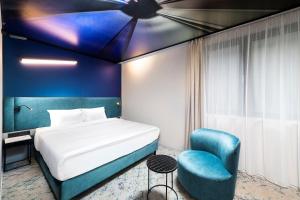 布达佩斯Three Corners Downtown Hotel的一间卧室配有一张床和一张蓝色椅子
