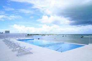 宫古岛Watermark Hotel & Resorts Okinawa Miyakojima的一个带椅子的游泳池,享有海景